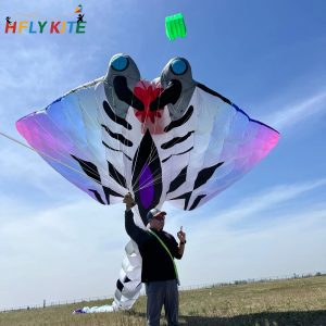 A white and black inflatable ray kite with purple accents and wide fins.