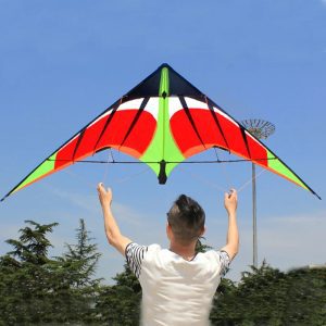 A red and green triangular stunt kite flying against a blue sky.