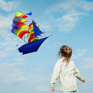 A sailing ship-shaped kite with a blue hull and multicolored rainbow sails.